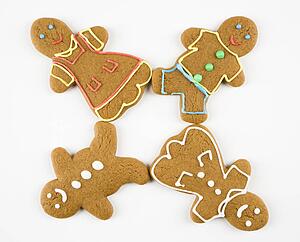Four male and female gingerbread cookies arranged with feet touching.