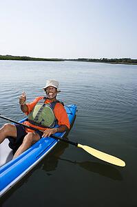 Middle-aged man in kayak, smiling and giving thumbs up gesture