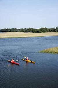 Two teenage boys kayaking through marshland on Bald Head Island, North Carolina.