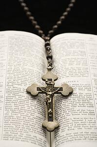 Rosary with crucifix lying on open Bible