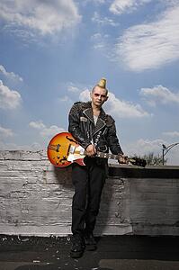 Portrait of mid-adult Caucasian male punk holding guitar.