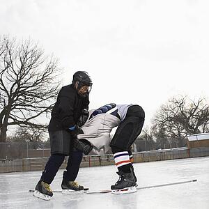 Ice hockey player boy roughing up another player on the ice rink.