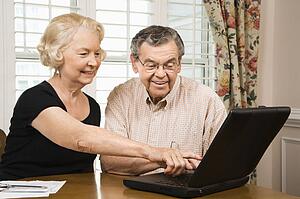 Mature Caucasian couple looking at laptop.