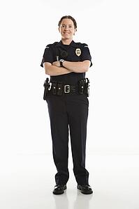 Portrait of mid adult Caucasian female law enforcement officer standing with arms crossed looking at viewer smiling.