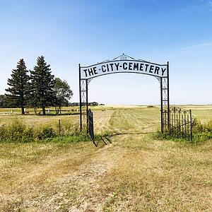 Entrance to rural cemetary in field with decorative iron gate.