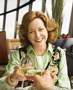 Caucasian mature couple toasting with white wine in restaurant.