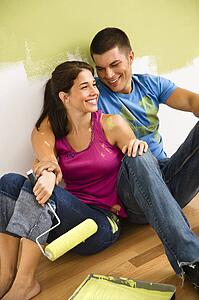 Couple sitting on floor smiling taking a break from painting home