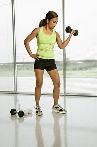 Mid adult woman lifting dumbbell with hand on hip
