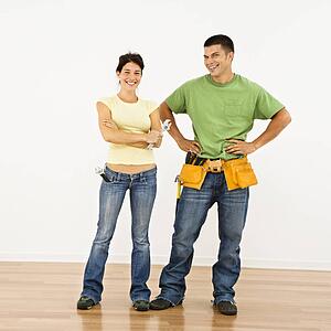 Couple with tools standing and smiling in home.