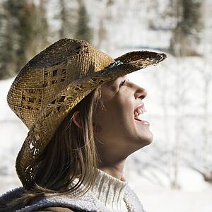 Young woman laughing wearing cowboy hat outdoors in winter