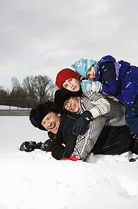 Family lying stacked on top of each other in snow