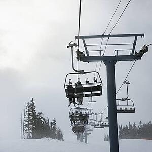 Skiers riding the chairlift in foggy winter weather.