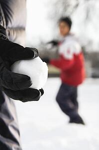 Boy holding snowball ready to throw at boy in background