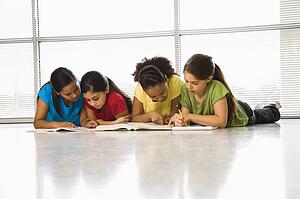 Girls lying on floor with schoolwork