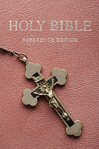 Crucifix lying on cover of closed Holy Bible