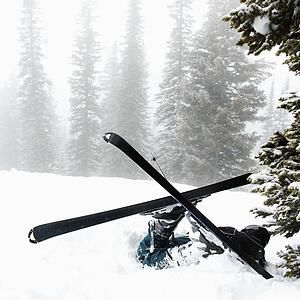Skiers lying in snow near tree after crash in fog.