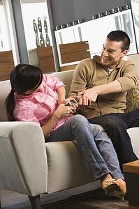 Couple on sofa fighting over TV remote