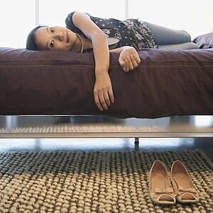 Portrait of Asian female lying on bed looking at viewer.