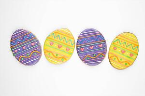 Four sugar cookies in shape of Easter eggs with decorative icing.