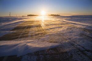 Ice covered road with sun rising in distance