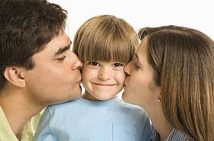 Mother and father kissing son on opposite cheeks
