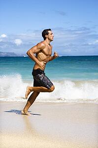 Physically fit man running on beach