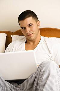 Man sitting in bed with laptop 