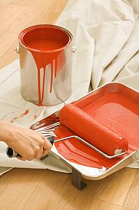 Hand holding paint roller in tray 
