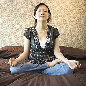 Woman meditating on a bed