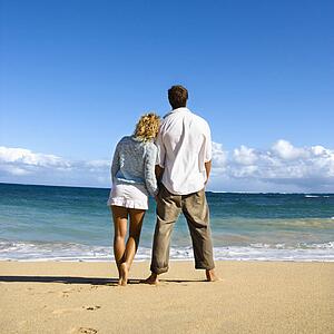 Attractive couple standing and leaning on each other looking out at ocean in Maui, Hawaii