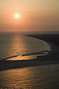 Aerial view of sun over Atlantic ocean and shoreline of Bald Head Island, North Carolina.