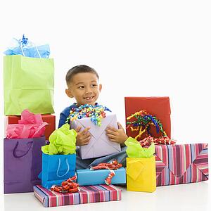 Asian boy sitting smiling with wrapped presents.