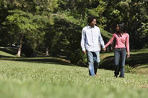 Smiling couple holding hands walking and talking in park