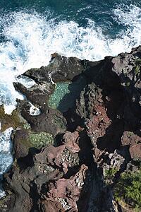 Aerial view of waves crashing on rocks in Maui, Hawaii.
