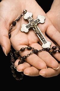 Woman's hands palm up cradling rosary with crucifix.