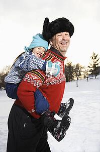 Middle aged man holding little girl piggyback style smiling and looking at viewer