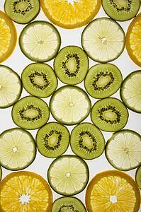 Assorted fruit slices arranged in pattern on white background.
