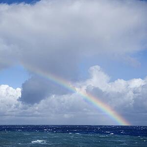 Seascape of the Pacific Ocean near Maui, Hawaii with rainbow and clouds.