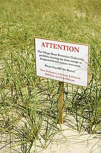Sign warning visitors not to walk on or disturb natural dune area.
