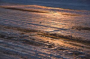 Close up of ice covered road with tire marks.