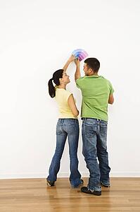 Couple holding color paint samples up to white wall