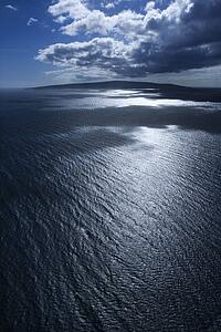 Island in Pacific ocean with puffy clouds