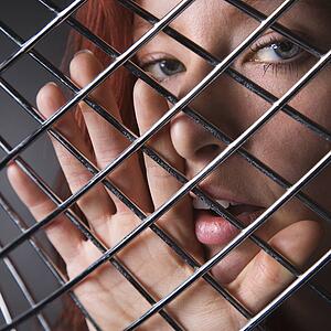 Pretty redhead young woman face and hand behind metal pattern