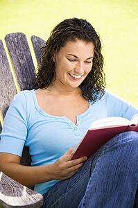 Smiling woman sitting and reading a book