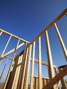 Low angle view of new construction framework for house with blue sky 