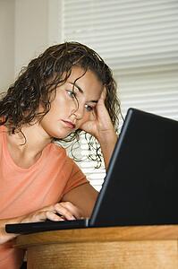 Pretty young adult brunette woman sitting and working on laptop computer