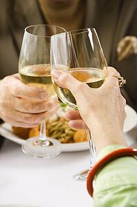 Caucasian mature couple toasting with white wine in restaurant.