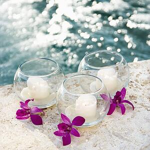 Three candles and three purple orchids by pool.