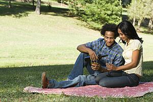 Couple having romantic picnic in park drinking wine