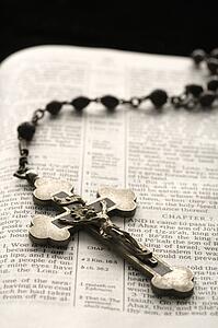 Rosary with crucifix lying on open Bible